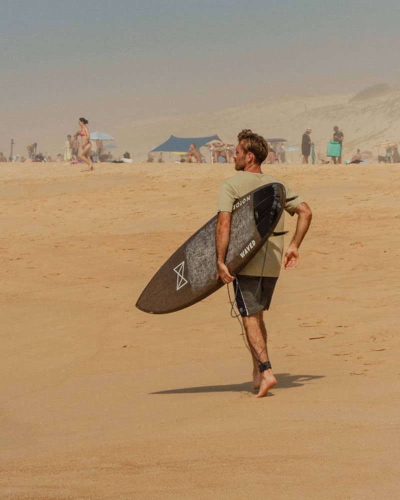 Surfeur marchant sur la plage avec sa planche à Hossegor